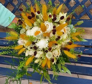 Bunter Blumenstrauß mit weißen, gelben und dunkelroten Blüten auf blauem Holzlattenzaun