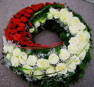 Trauerkranz aus roten und weißen Rosen mit Schleierkraut und grünen Blättern