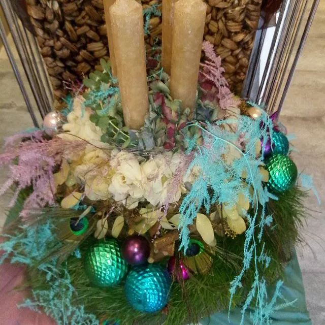 Weihnachtlicher Adventskranz mit zwei Kerzen, Tannenzweigen, getrockneten Blumen und bunten Christbaumkugeln